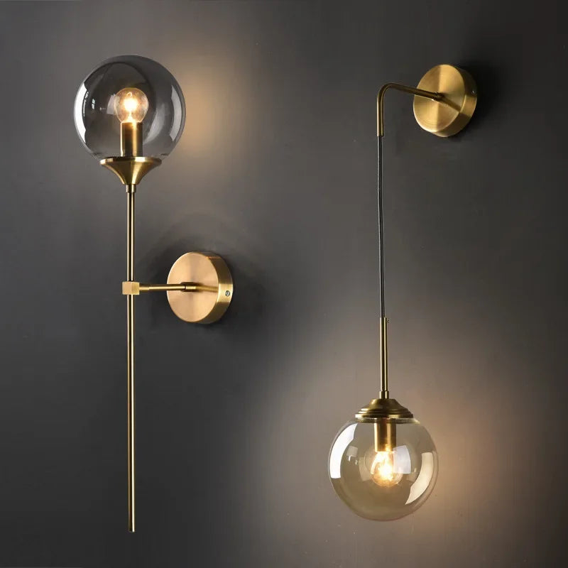 Glass globe wall sconces on slim brass stems against a dark wall