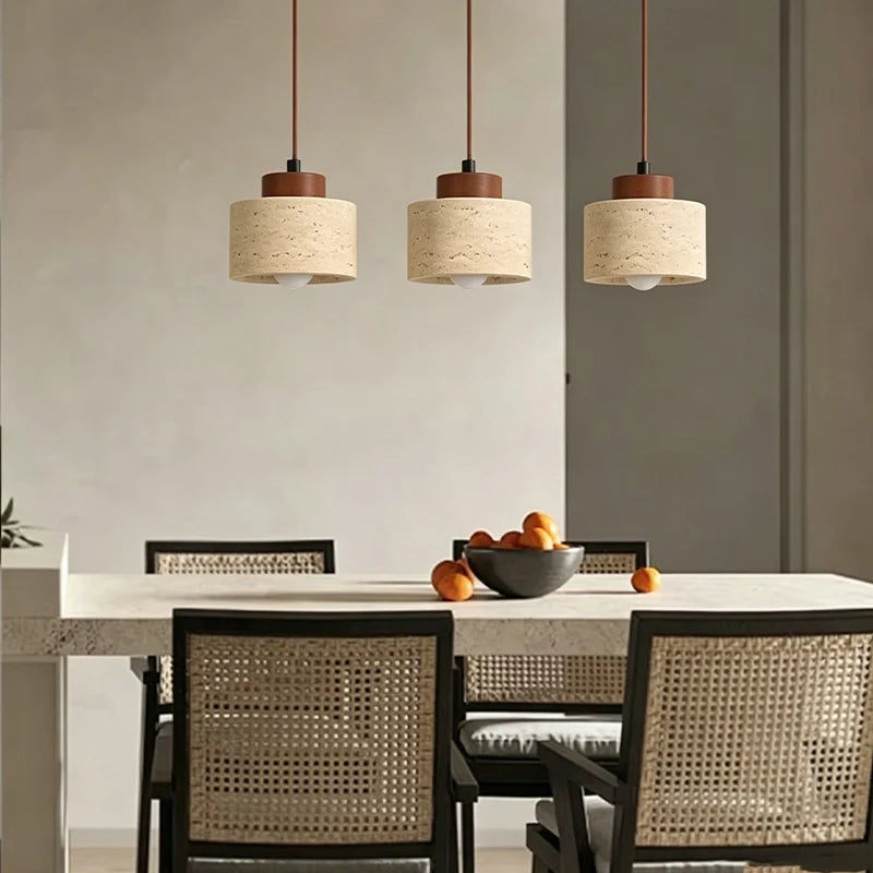 Three travertine stone pendant lights hanging in a row above a dining table
