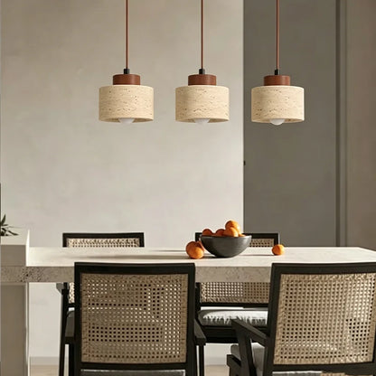 Three travertine stone pendant lights hanging in a row above a dining table