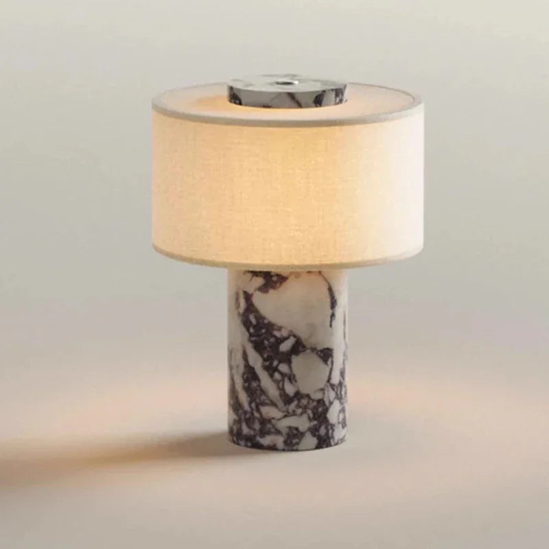 Marble column table lamp with a scalloped shade on a side table