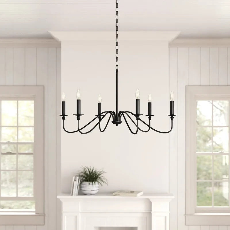 Black iron candlestick chandelier above a table in a white room
