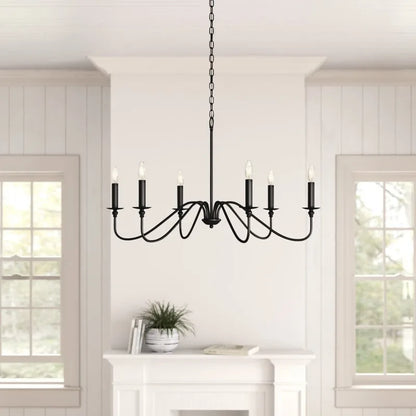 Black iron candlestick chandelier above a table in a white room